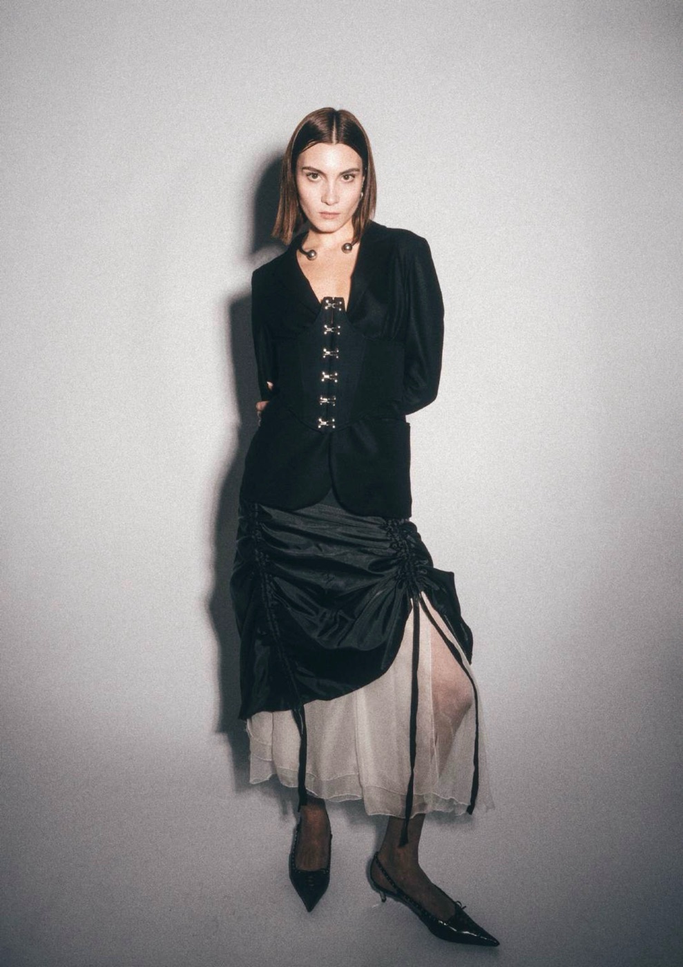 Model in a black jacket with corset lacing and a gathered taffeta skirt over organza