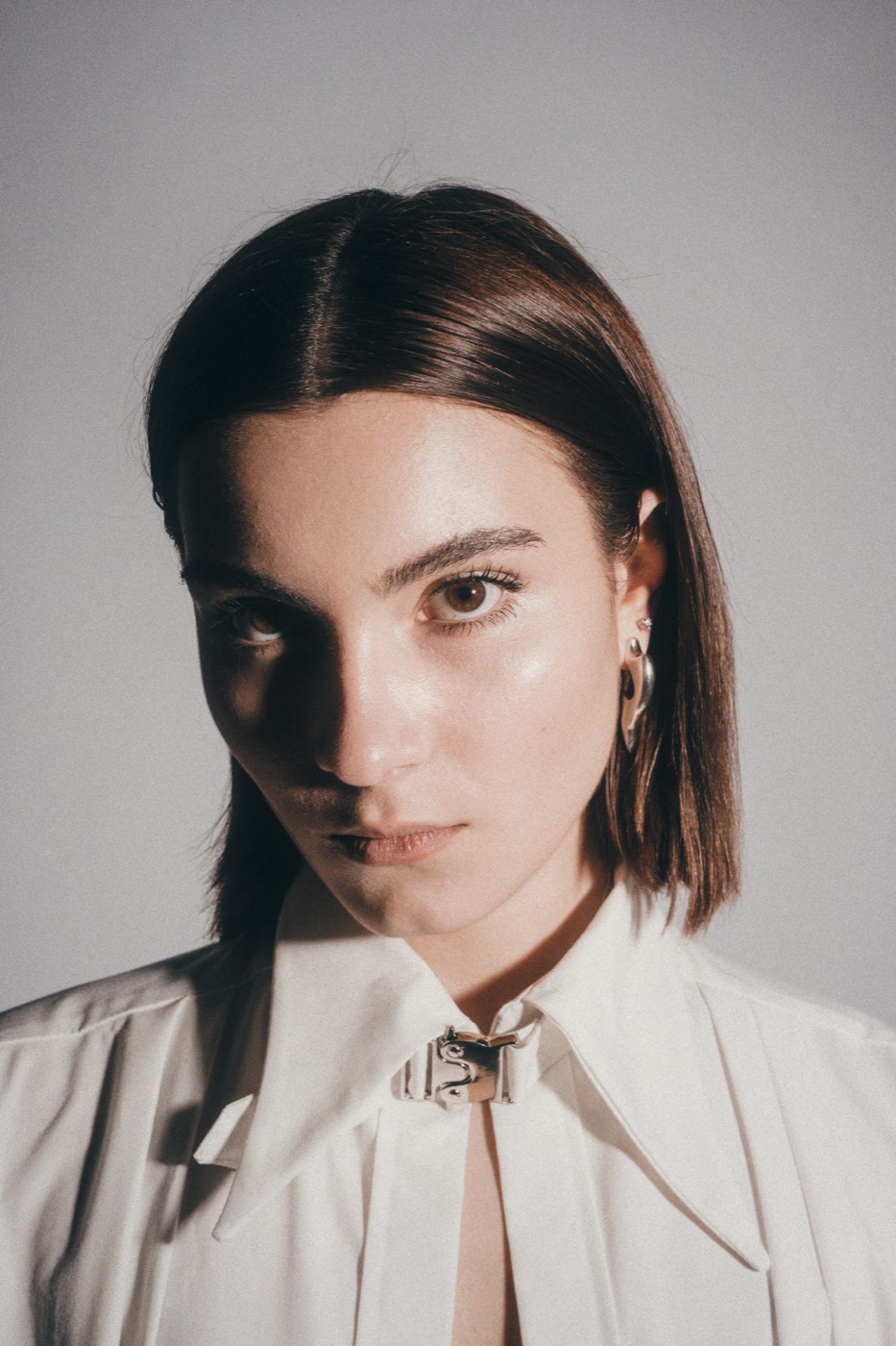 Close portrait of the model in a white collar with a metal clasp