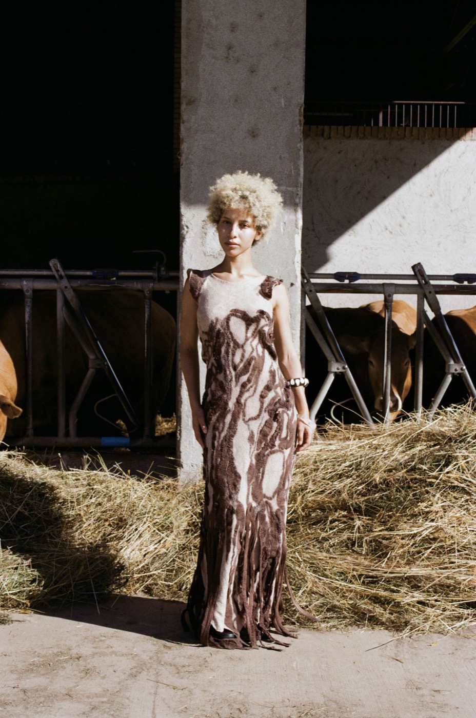 Long felted dress with brown organic patterns, standing in a barn