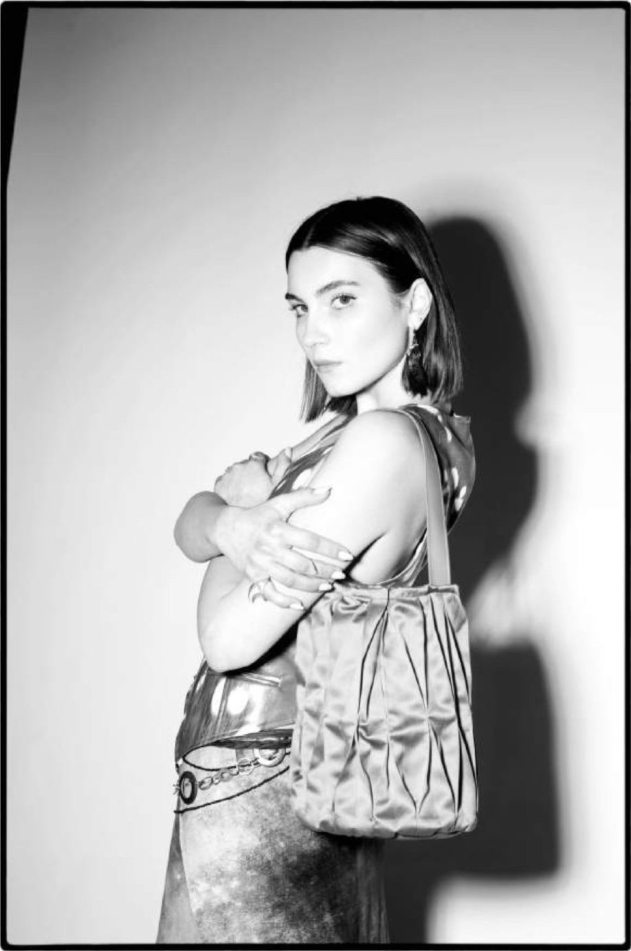 Black and white portrait of a model holding the folded satin bag